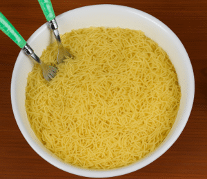 Sweet Seffa Vermicelli with Almonds being prepped in a white bowl before steaming, shown on a wooden surface.