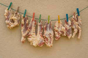 Fresh meat strips hung to dry traditionally with clothespins, part of preparing Qadeed Recipe.
