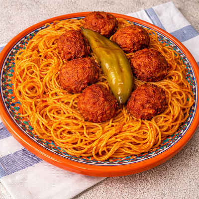 pasta with minced meat and rich recipe served on an orange plate with spicy sauce and meatballs