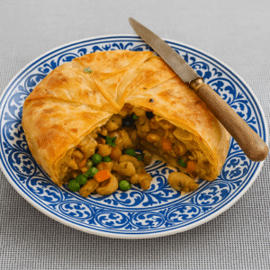 Flaky Moroccan chicken dish served on a golden plate with spiced vegetables and crispy phyllo layers.