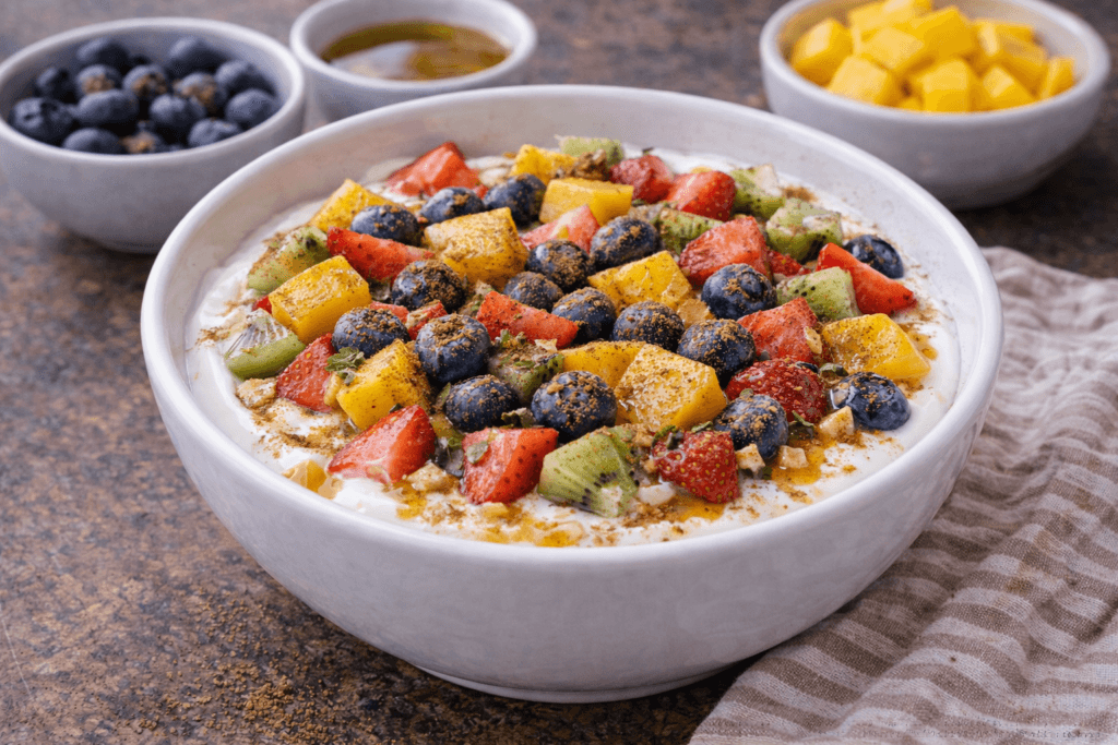 fruit yogurt bowl topped with cinnamon and honey