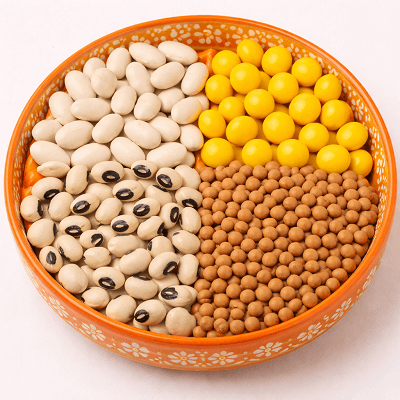 A decorative orange bowl filled with the healthiest plant-based foods including white beans, yellow beans, black-eyed peas, and lentils