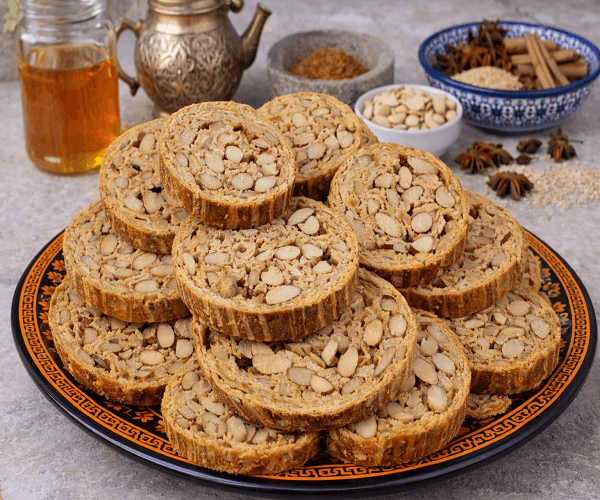Moroccan almond fekkas cookies served on decorative orange plate with honey and spices in background
