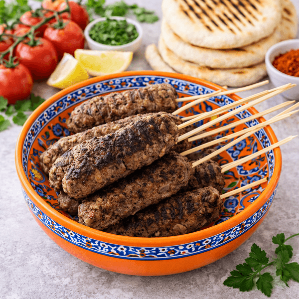 Grilled beef kofta skewers served on a traditional orange Moroccan plate
